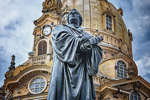Достопримечательности Дрездена.  Бронзовый памятник Мартину Лютеру на новой рыночной площади Дрездена прямо перед зданием церкви Девы Марии (Frauenkirche)